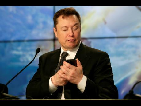 Elon Musk, founder, CEO and chief engineer/designer of SpaceX, pretends to search for an answer to a question on a cell phone during a news conference after a Falcon 9 SpaceX rocket test flight at the Kennedy Space Center in Cape Canaveral, Florida, on Jan