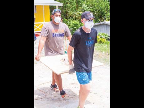 Chad Ziadie and Richard Lechler carry building material.