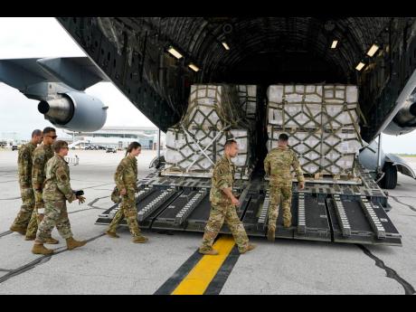 Crew members of a C-17 begin to unload baby formula at the Indianapolis International Airport on Sunday. The 132 pallets of Nestlé Health Science Alfamino Infant and Alfamino Junior formula arrived from Ramstein Air Base in Germany.