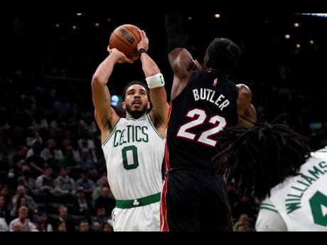 Boston Celtics forward Jayson Tatum (0) shoots over Miami Heat forward Jimmy Butler (22) during the second half of Game 4 of the NBA basketball playoffs Eastern Conference finals, Monday, May 23, 2022, in Boston. 