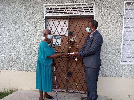 Parish manager for the Clarendon Health Department, Joseph Grant, accepts the symbolic handover from Angela Miller, a member of the health committee.