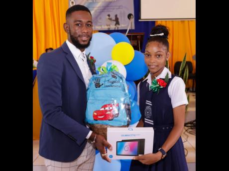 Tira Thompson of Linstead Primary and Junior High receives a tablet and gift basket from Fabian Gordon, Sagicor Life adviser. Tira is among 10 students who received tablets and gift baskets from the Sagicor Foundation as they partnered with True United Sis
