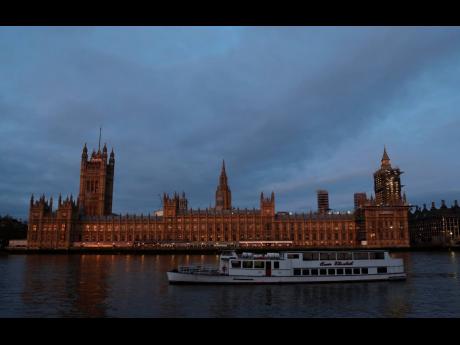 The Palace of Westminster viewed from the south side of the embankment by the River Thames just after dawn.