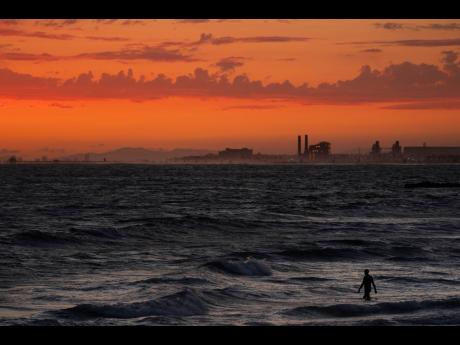 Credit: AP A man wades into the ocean at sunset on June 22, 2021, in Newport Beach, California. The National Oceanic and Atmospheric Administration announced yesterday that the amount of carbon dioxide in the atmosphere in May averaged 421 parts per million, more tha