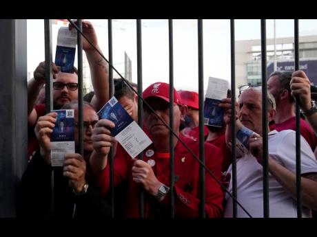  
Liverpool fans show tickets and wait in front of the Stade de France prior the Champions League football final between Liverpool and Real Madrid, in Saint Denis near Paris, Saturday, May 28, 2022. Police deployed tear gas on supporters waiting in long li