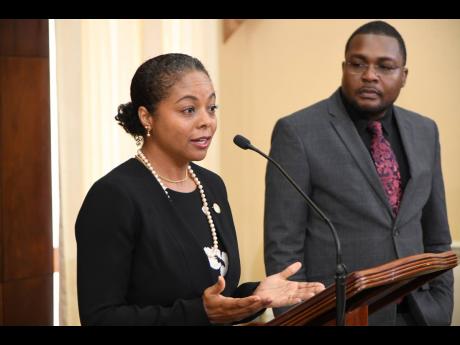 Minister without Portfolio Robert Morgan listens as Marlene Malahoo Forte, minister of legal and constitutional affairs, addresses journalists at Jamaica House on April 6.