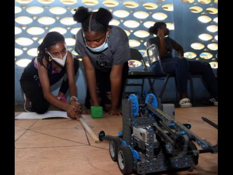 Youths from inner-city communities learning robotics during a stem and football camp hosted by UpRising Academy at Tarrant High School in St Andrew  recently.