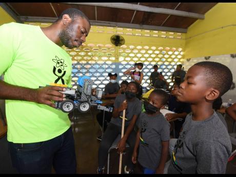 Jerome Morrison (left), teaches youths from inner-city communities about robotics during a STEM camp hosted by UpRising Academy at Tarrant High School in St Andrew on May 22. The children were also taught the rudiments of futsol and coding over two days.