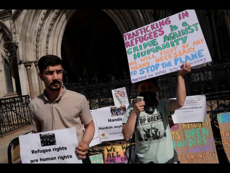 Protesters stand outside the High Court, where the ruling on Rwanda deportation flights is taking place, in London yesterday. 