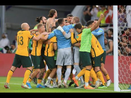 Australian players celebrate after winning a penalty shoot-out during the World Cup 2022 qualifying play-off match between Australia and Peru in Al Rayyan, Qatar yesterday.