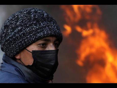 A protester stands near a burning barricade of tyres blocking a highway on the second day of nationwide demonstrations against the government of Guillermo Lasso, called mainly by Indigenous organisations, in Cotopaxi, Ecuador, yesterday.