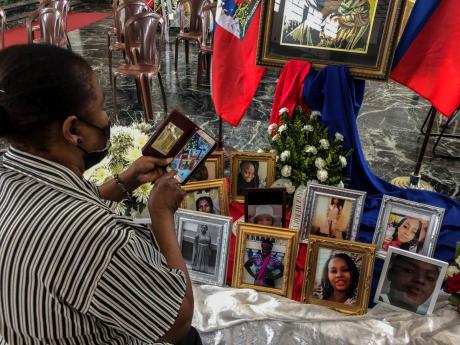 A woman takes a photo of the images of the 11 Haitian women who died last month when the overloaded boat they were in capsized, at a church in San Juan, Puerto Rico on Wednesday.