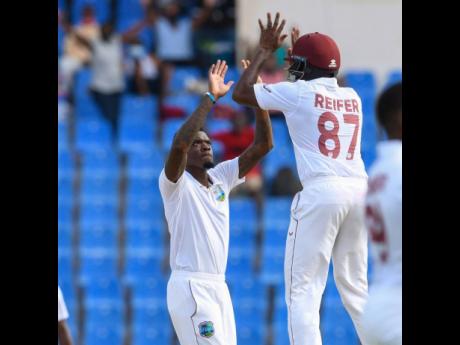 Fast bowler Alzarri Joseph (left) of the West Indies celebrates the dismissal of Tamim Iqbal of Bangladesh with teammate Raymon Reifer  during the second day of the  first Test between Bangladesh and West Indies at Sir Vivian Richards Cricket Stadium in No
