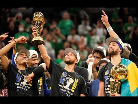 Golden State Warriors guard Stephen Curry (centre) holds up the Bill Russell Trophy for Most Valuable Player after the Warriors defeated the Boston Celtics in Game 6 to win basketball’s NBA Finals on Thursday, June 16 in Boston. 