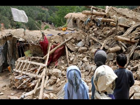 Afghan children stand near a house that was destroyed in an earthquake in the Spera District of the southwestern part of Khost Province, Afghanistan, on Wednesday, June 22.