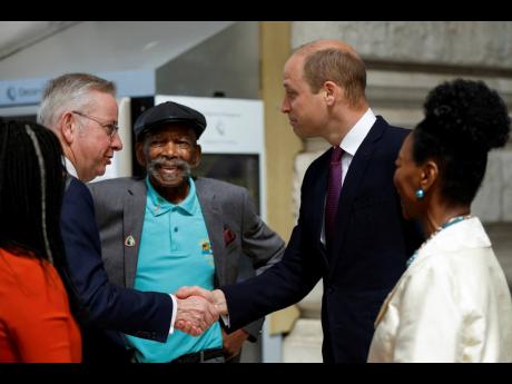 Credit: John Sibley British Secretary of State for Levelling Up, Housing and Communities Michael Gove, left, shakes hands with Britain’s Prince William next to Windrush passenger Alford Gardner, background and Baroness Floella Benjamin.