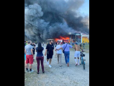 People watch as smoke bellows after a Russian missile strike hit a crowded shopping mall, in Kremenchuk, Ukraine, Monday, June 27.