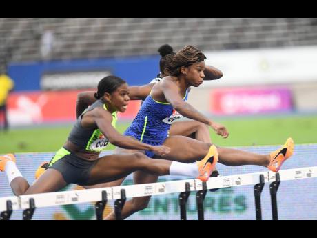 Megan Tapper (left) and Britany Anderson (right) clear the last hurdle in the  women’s 100m hurdles final at the JAAA National Senior and Junior Championships on Sunday at the National Stadium. Anderson won in 12.53 seconds while Tapper was second in 12.