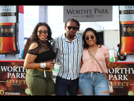 Caught in the middle while checking out the Worthy Park Estate booth, Garfield Williams (centre) of Groomed MEN Apparel gets sandwiched by Tigest Perry and Trisha Wong. 