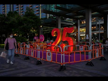 A woman walks past a sculpture to celebrate the 25th anniversary of Hong Kong handover to China, in Hong Kong, Friday, June 24, 2022.