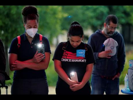 Naiyolis Paloma (centre) prays with others during a community vigil for the dozens of people found dead Monday in a semitrailer containing suspected migrants as well as those who received heat-related injuries, on Tuesday, June 28.