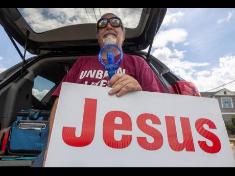 
Anti-abortion advocate Edwin Shanks uses a small fan to cool himself as he and others gather outside the Women’s Health Care Center in New Orleans on June 30. 