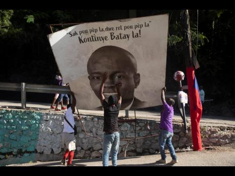 Supporters of slain Haitian President Jovenel Moise place a sign of him that reads ‘The purse of the people must remain with the people. Continue the fight’, in the Petion-ville area of Port-au-Prince, Haiti, on July 7.