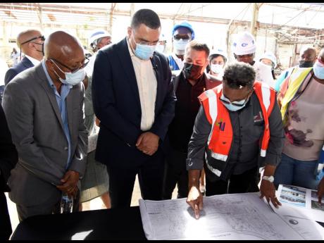 From left: Michael Hue, mayor of Morant Bay; Prime Minister Andrew Holness; and Senator Matthew Samuda, minister without portfolio in the Ministry of Economic Growth and Job Creation, look over the  blueprint of the Morant Bay Urban Centre with architect B