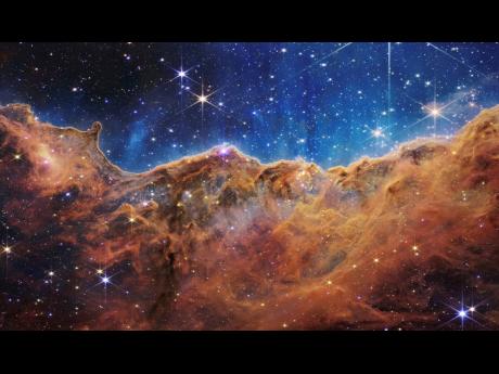 This image released by NASA shows the edge of a nearby, young, star-forming region NGC 3324 in the Carina Nebula. 