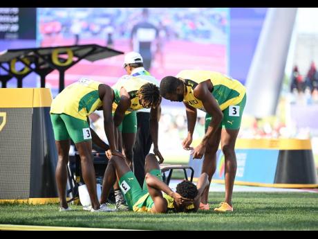 Jamaican athletes check on the status of national champion Jevaughn Powell after the exertions of a 4x400-metre qualifier on day nine of the World Athletics Championships in Eugene, Oregon yesterday.