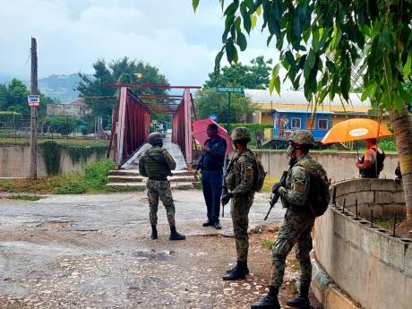 Credit: Photo by Roxroy McLean Security personnel near ‘Red Bridge’ in Waterhouse, St Andrew, in the aftermath of a drive-by shooting Tuesday. One man was killed.