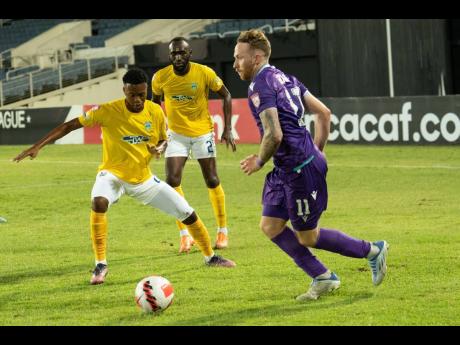 Credit: Concacaf.com Pacific FC’s Joshua Heard (right) steps away from Waterhouse defenders, Damion Binns (centre) and substitute Zain Hylton during a Scotiabank Concacaf League encounter at Sabina Park on Tuesday.
