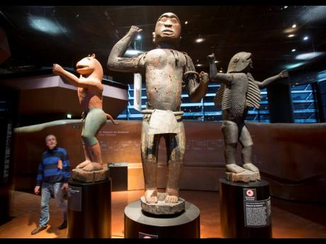 A visitor looks at wooden royal statues of the Dahomey kingdom, dated 19th century, at the Quai Branly museum in Paris, France, in November 2018. 