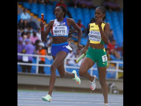 Jamaica’s Abigail Campbell (right) chases the United States’ Madison Whyte on the third leg of a 4x400 mixed relay heat on day one of the World Athletics U20 Championships in Cali, Colombia yesterday. 