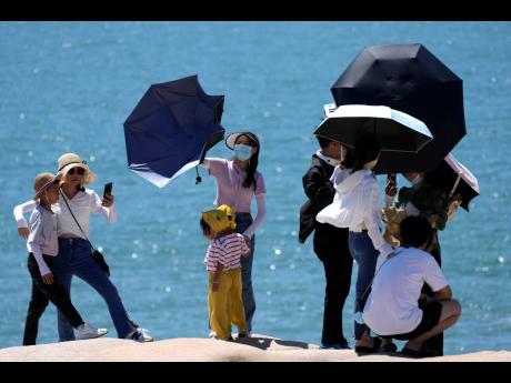Tourists pose for photos on the waterfront at the 68-nautical-mile scenic spot, the closest point in mainland China to the island of Taiwan, in Pingtan in southeastern China’s Fujian Province yesterday. 