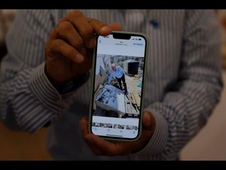 Koby Abergel, an Israeli art dealer, shows a photo on his phone of him in the West Bank city of Bethlehem with a painting by the secretive British graffiti artist Banksy.