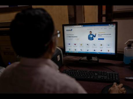 Credit: AP A man looks at the website of Policybazaar at a local insurance company office in Mumbai, India, on Wednesday, August 10.