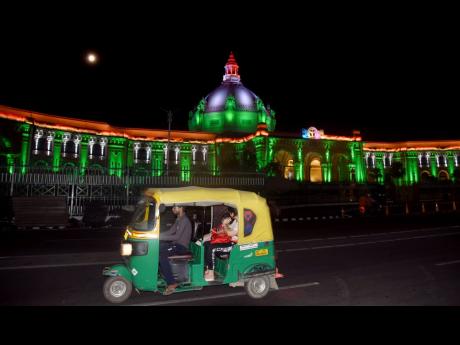 An autorickshaw (tuk tuk) passes the illuminated Vidhan Bhavan (Assembly House) in the northern India city of Lucknow, capital of Uttar Pradesh.
