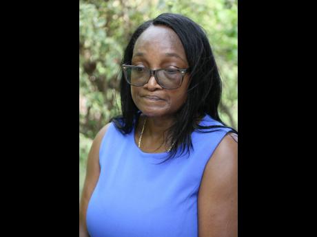 Evan Reader Clarke struggling to fight back the tears as mourned her brother, Delroy ‘Bess’ Reader, a taxi operator who was shot dead on Tuesday night in St Catherine. 
