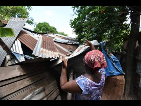 Credit: Kenyon Hemans/Photographer Dezreen Miller shows damage done to her home when an ackee tree fell through the roof of the structure. Pieces of old plywood, sheets of zinc and tarpaulin are used to keep out the elements.