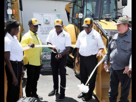 Credit: Christopher Serju Minister of Agriculture and Fisheries Pearnel Charles Jr (centre) cuts the ribbon during the handover ceremony for two four-wheel drive CAT 426F2 backhoes to the Rural Agricultural Development Authority (RADA) on Wednesday at the Agro Investment Corporatio