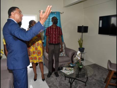 Reginald Henclewood (right) gives Prime Minister Andrew Holness (left) and St Andrew South Western Member of Parliament Dr Angela Brown Burke a tour of his new home in Majesty Gardens Phase 1A after receiving the keys on Wednesday. 