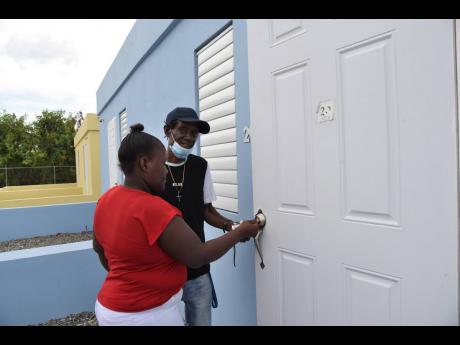 Dennis Garvey and his daughter, Trudy-Ann Garvey, open the door to their new home in Majesty Gardens Phase 1A shortly after receiving the keys on Wednesday.