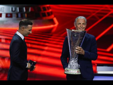 Former German player Karl-Heinz “Charly” Korbel (right) places the trophy during the Europa League draw in Istanbul, Turkey yesterday.