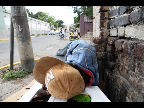 Credit: Rudolph Brown/Photographer A homeless man rests along the sidewalk on Hanover Street, Kingston, on Tuesday.
