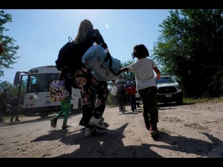 FILE – A migrant family from Venezuela move to Border Patrol transport vehicle after they and other migrants crossed the US-Mexico border and turned themselves in Del Rio, Texas, June 16, 2021. 