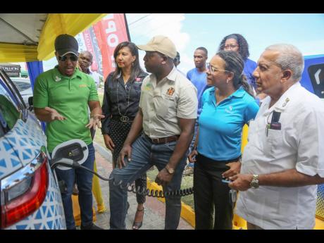 Andre Mangue, marketing manager, JPSCo Ltd shows the new charging port at Texaco Mineral Heights service station  to Karoline Smith, general manager of SOL Jamaica SRL, Pearnel Charles Jr, MP Clarendon SE; Brenda-Lee Martin, VP Asset Management & Treasury,