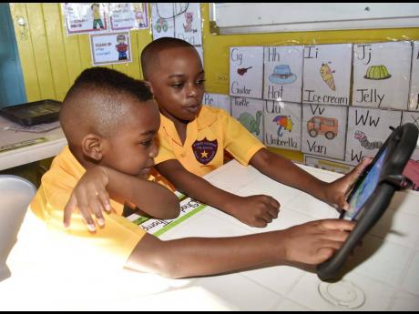 Credit: Kenyon Hemans From left: Ricardo Frazer and Nathan Whyte, students of the Kinder Campus in St Catherine, play with their tablet before the start of school on Monday, September 5.