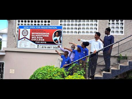 Dave Soares (second left), principal of Monsignor Gladstone Wilson College for Boys, a new high school, along with his pioneering students pointing to the school’s sign. From left: students Javier Fisher, Richardo Gordon, Mark Wilson, Dujuan Anderson and