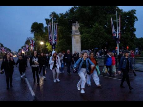 Credit: AP People rush to get a spot to see the cortege carrying the coffin of late Queen Elizabeth II, before it arrives at Buckingham Palace in London, on Tuesday, September 13. Britain’s longest-reigning monarch died September 8, after 70 years on the throne. Sh